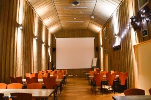 una sala conferenze con tavoli, sedie e schermo bianco di Merilän Kartano a Utajärvi