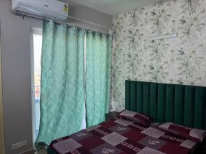 a bedroom with a green bed and a window at Pindora Stays in Ludhiana