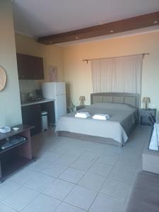 a bedroom with a large bed and a kitchen at Petani Beachside Accommodation in Vóvikes