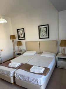 a bedroom with two beds and two lamps and two tables at Popi Studios in Kos