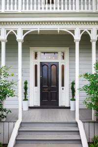 a black door on a white house with a porch at Andelin Guest House in Auckland