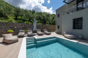 a swimming pool with lounge chairs and a house at Kalma Luxury Villas in Kalamata