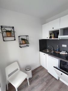 a white kitchen with a white chair and a sink at Vue Mer sur Juno Beach - Studio in Courseulles-sur-Mer