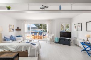 a white living room with a couch and a tv at Ancla 1 in Port d'Andratx
