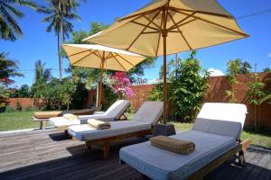 a patio with two chairs and an umbrella at Villa Taman Kanti in Ubud