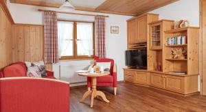 ein Wohnzimmer mit einem roten Stuhl und einem Tisch in der Unterkunft Haus Bergland in Fischen im Allgäu