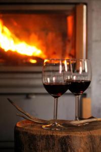 two glasses of red wine sitting on a table in front of a fireplace at River cabin Tapio in Inari