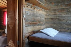 a bedroom with a wooden wall with a bed in it at River cabin Tapio in Inari