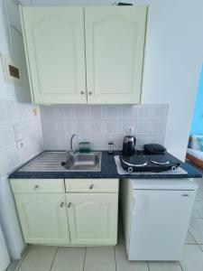 a kitchen with white cabinets and a sink at Calypso Studios in Amoudi