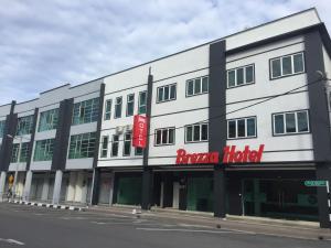 a large white building with a red sign on it at Brezza Hotel Sitiawan in Sitiawan