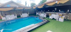 a swimming pool with white tables and chairs next to at Lazeto Hotel and Resorts in Zongon Daji