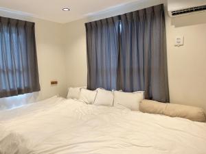 a white bed with pillows in front of a window at カリマタテラス宮古島 in Miyako-jima
