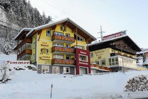 a yellow building in the snow next to a mountain at Hotel Posauner in Sankt Veit im Pongau