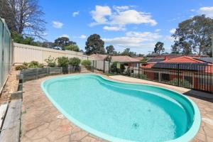 a swimming pool in the backyard of a house with a fence at Escape from Relaxing Poolside House 3B in Narellan