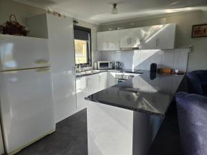 a kitchen with white cabinets and a black counter top at Wudinna Farm View in Wudinna