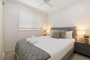 a bedroom with a large white bed with a window at Escape from Relaxing Poolside House 3B in Narellan
