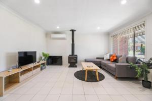 a living room with a couch and a fireplace at Escape from Relaxing Poolside House 3B in Narellan