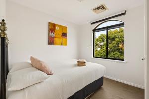 a white bedroom with a bed and a window at Group stays for Friends Families Weddings and Events Walkable to Fremantle and attractions Super Spacious with garden and courtyard and balcony and parking for 2 cars Sleeps 6 3BD 3BR in Fremantle