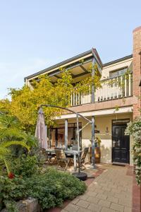 an outdoor patio with a table and an umbrella at Group stays for Friends Families Weddings and Events Walkable to Fremantle and attractions Super Spacious with garden and courtyard and balcony and parking for 2 cars Sleeps 6 3BD 3BR in Fremantle