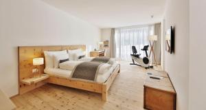 Schlafzimmer mit einem Bett, einem Schreibtisch und einem Laufband in der Unterkunft Relais & Châteaux IN LAIN Hotel Cadonau in Brail