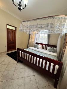 a bedroom with a canopy bed and a window at GRACE ViLLA in Kitende +3 photos