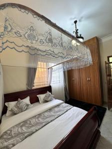 a bedroom with a large bed with a canopy at GRACE ViLLA in Kitende