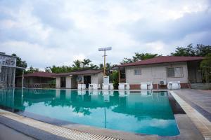 a swimming pool with chairs and a building at White Petals Resort in Bangalore