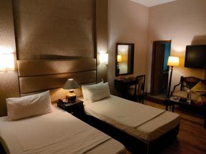 a hotel room with two beds and a mirror at The Exclusive House in Peshawar