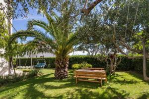 a wooden bench sitting next to a palm tree at Hostel Oktarin in Kaštela