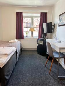 a hotel room with a bed and a desk and a window at Värdshuset Hwitan in Falkenberg