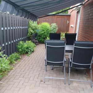 a patio with three chairs and a table and a fence at Heideglück in Visselhövede +10 photos