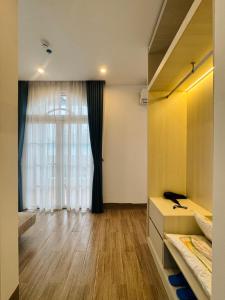 a bedroom with a large window and a wooden floor at Blue Hotel Sunset Town Phu Quoc in Phú Quốc