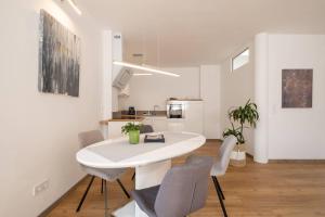 a white dining room with a white table and chairs at eifel5starIV Burgfriedstraße in Daun +6 photos