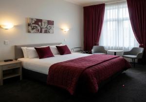 a hotel room with a large bed with a red blanket at The Grand Wanganui in Whanganui