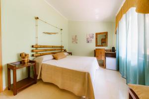 a bedroom with a bed and a table and a window at Oasi Scolacium in Villaggio Le Rocelle