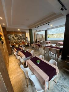a restaurant with tables and chairs in a room at Benhas Hotel Bukittinggi in Bukittinggi