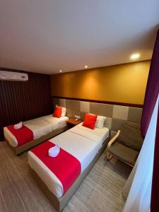 a hotel room with two beds and a chair at Benhas Hotel Bukittinggi in Bukittinggi