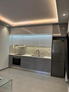 a kitchen with gray cabinets and a sink and a refrigerator at Fabio apartment in Amarynthos