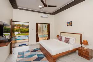 a bedroom with a bed and a tv and a pool at Mango Serene by Roamigo in Karjat