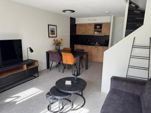 a living room with a table and a couch and a kitchen at Prins Heerlijk Amelander Kaap 81 in Hollum