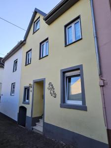 a white house with a yellow door and windows at Gästenzimmer Louis in Ediger-Eller +1 photo