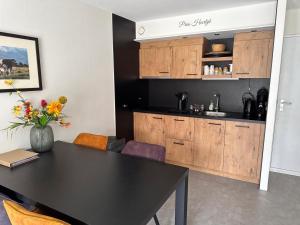 a kitchen with a black table and wooden cabinets at Prins Heerlijk Amelander Kaap 81 in Hollum