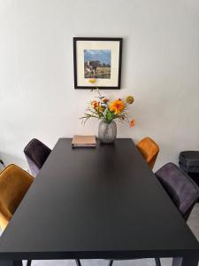 a black dining room table with a vase of flowers at Prins Heerlijk Amelander Kaap 81 in Hollum +26 photos