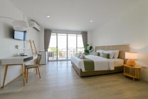 a hotel room with a bed and a desk and a bed and a window at Little Home Ao Nang in Ao Nang Beach