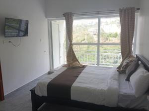 a bedroom with a bed and a large window at Prithivee Homestay in Kotagiri