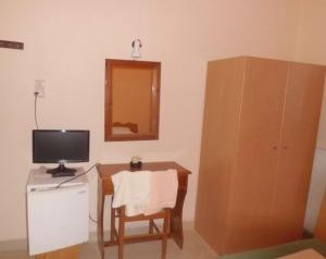a room with a desk with a television and a chair at Hotel Marmarinos in Egina