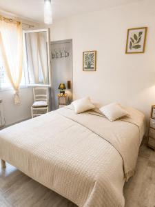a white bedroom with a large bed and a chair at Séjour bercé par la Mer in Jard-sur-Mer