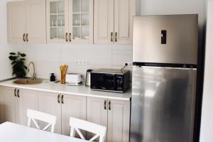 a kitchen with white cabinets and a stainless steel refrigerator at Casa ZUGO in Borsec
