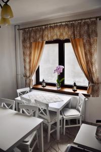 a dining room with white tables and chairs and a window at Casa ZUGO in Borsec