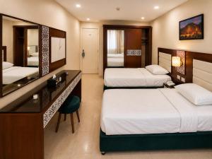 a hotel room with two beds and a mirror at Karnak Hotel Luxor in Luxor
